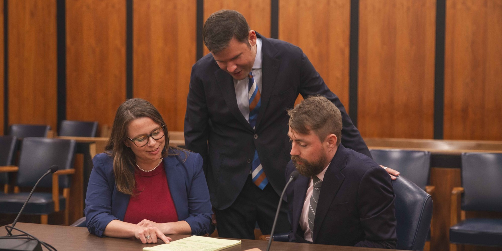 Three lawyers in courtroom looking at document banner Oct 2025